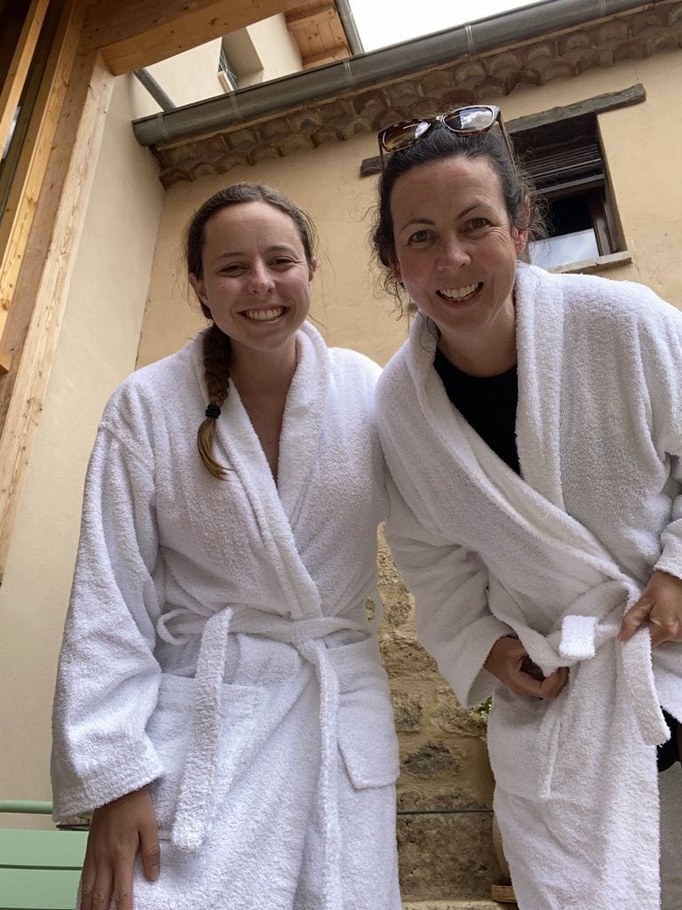 Two women wearing white robes and smiling