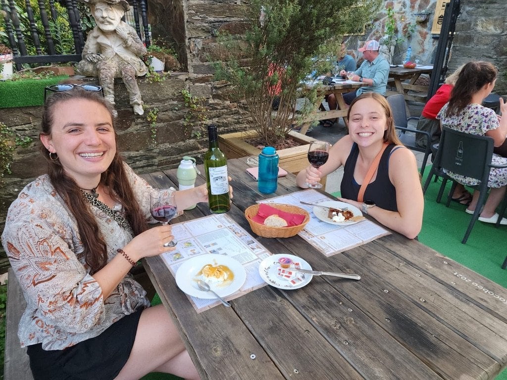 Two women smiling over dinner at a table outside along the Camino Francés