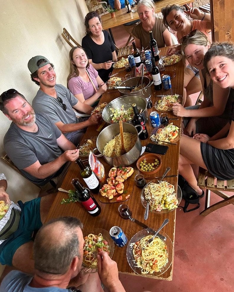 A large group of people smiling around a table at dinner after hiking along the Camino Francés