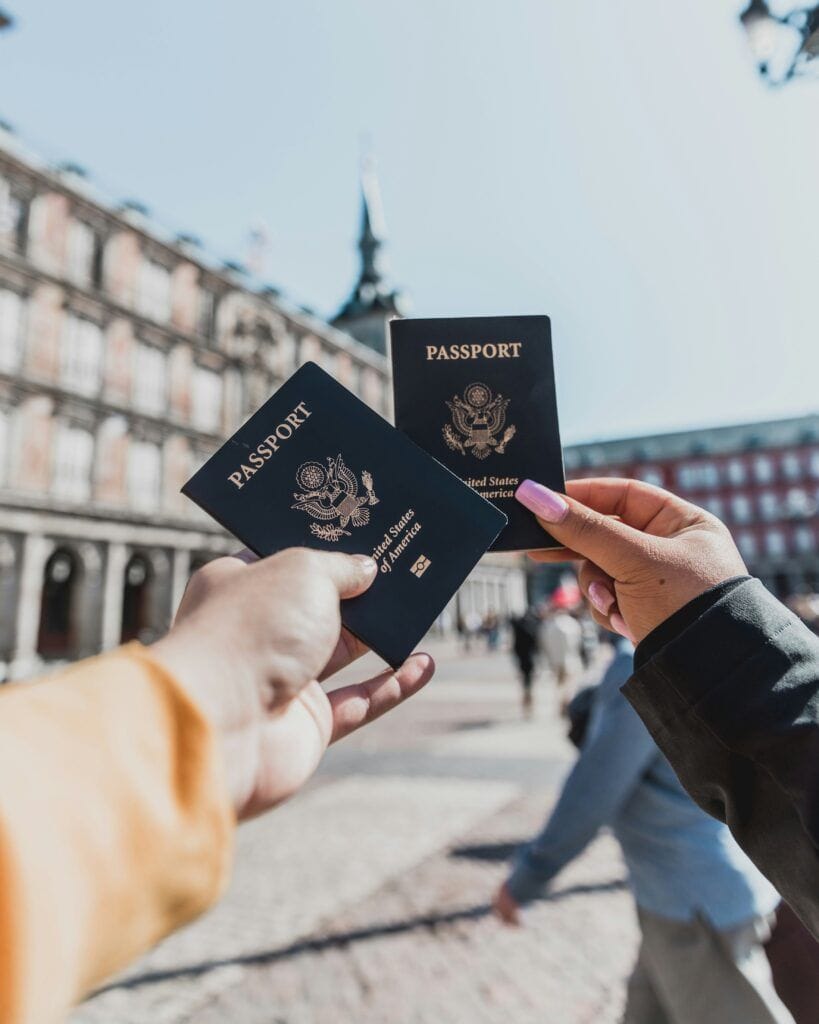 Two people holding passports up together in a European city square