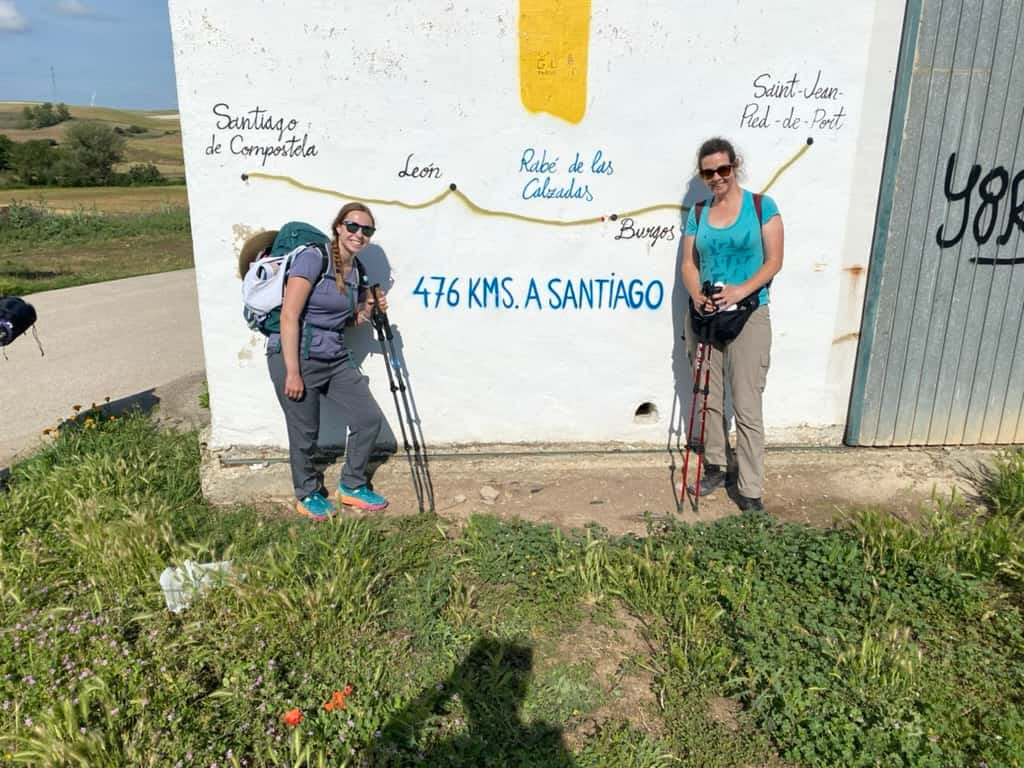 Two women smiling at a Camino Francés mural