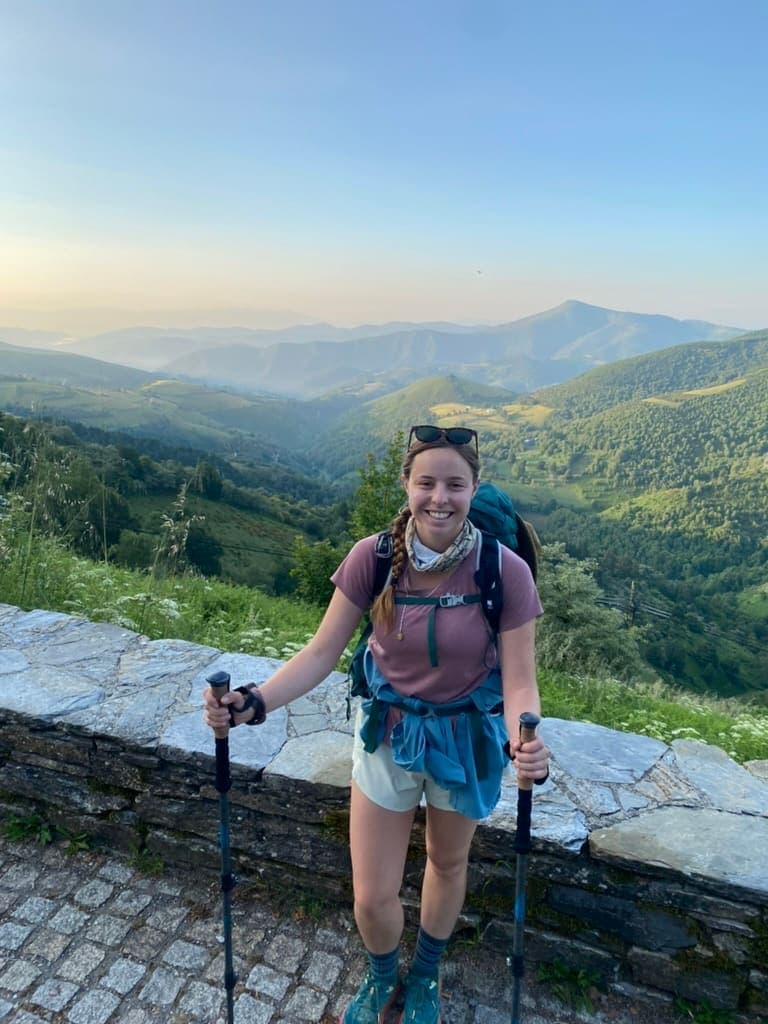Mikala smiling with mountains in the background while hiking the Camino Francés.