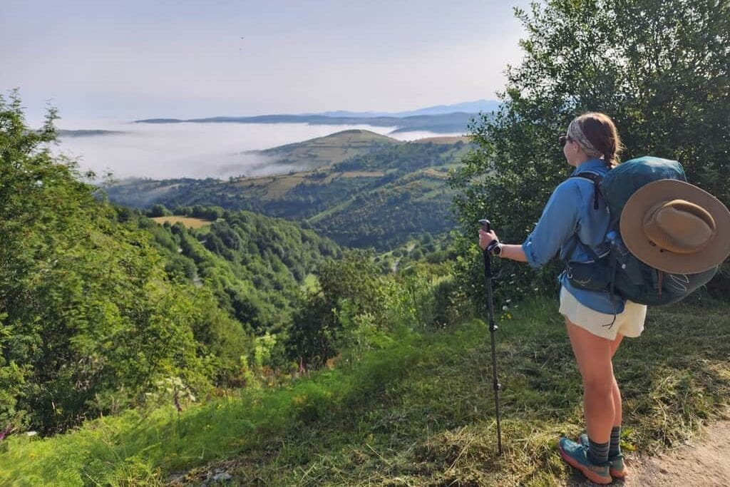 Female hiker looking down over a mountain valley below