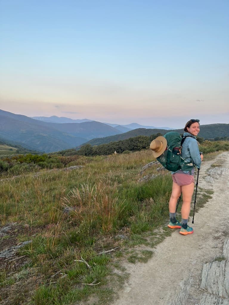 Mikala smiling with mountains in the background on the Camino Francés route of the Camino de Santiago.