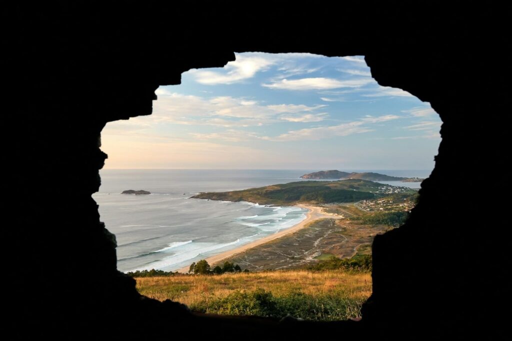 View through a cave opening of the coastline of Ferrol, Spain, the typical starting point for the Camino Inglés.
