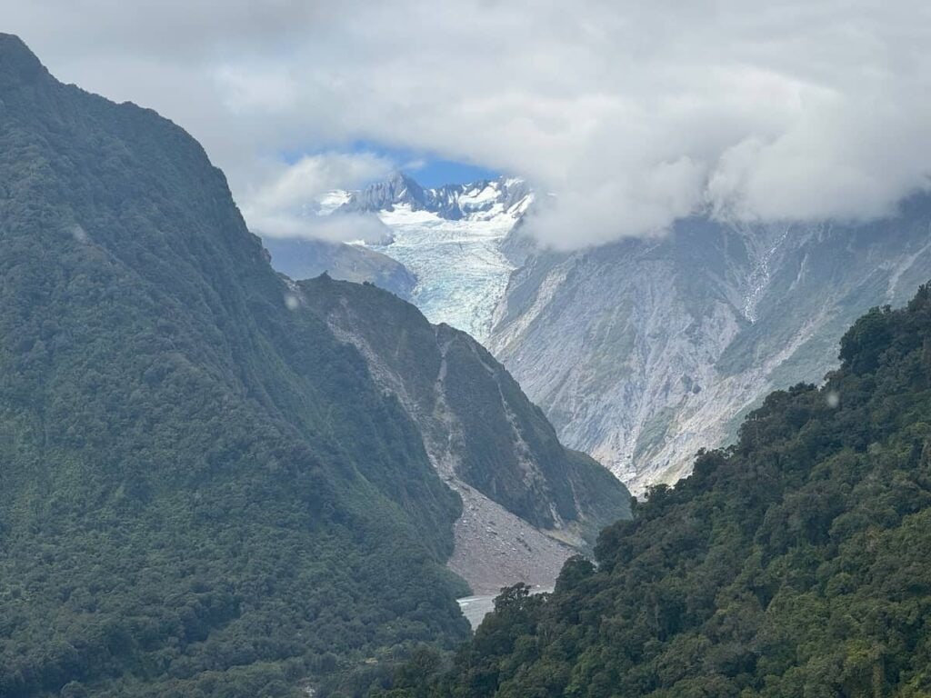 View of Fox Glacier from a helicopter high above a river valley below.