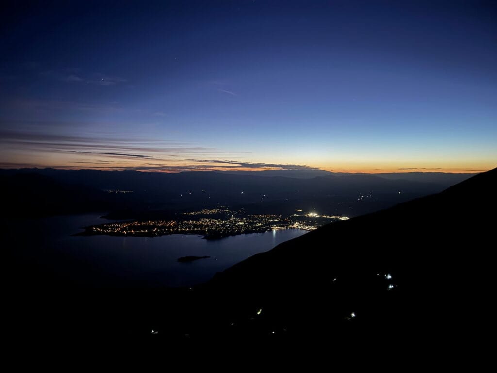 Sliver of light appearing before sunrise over Lake Wānaka and surrounding mountains during the Roy's Peak sunrise hike.