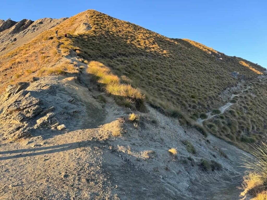 Two paths going up to the summit of Roy's Peak. One is straight ahead and much steeper while the other goes to the right and wraps around the mountain, rising more gradually.