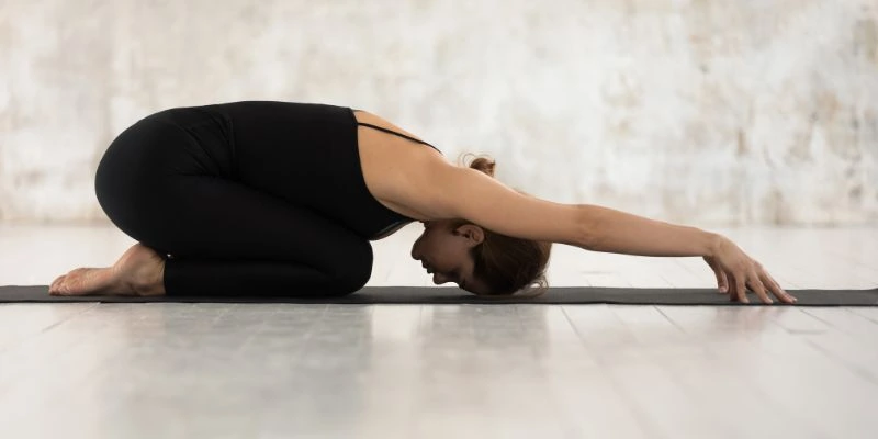navasana posture du bateau en tenue rouge