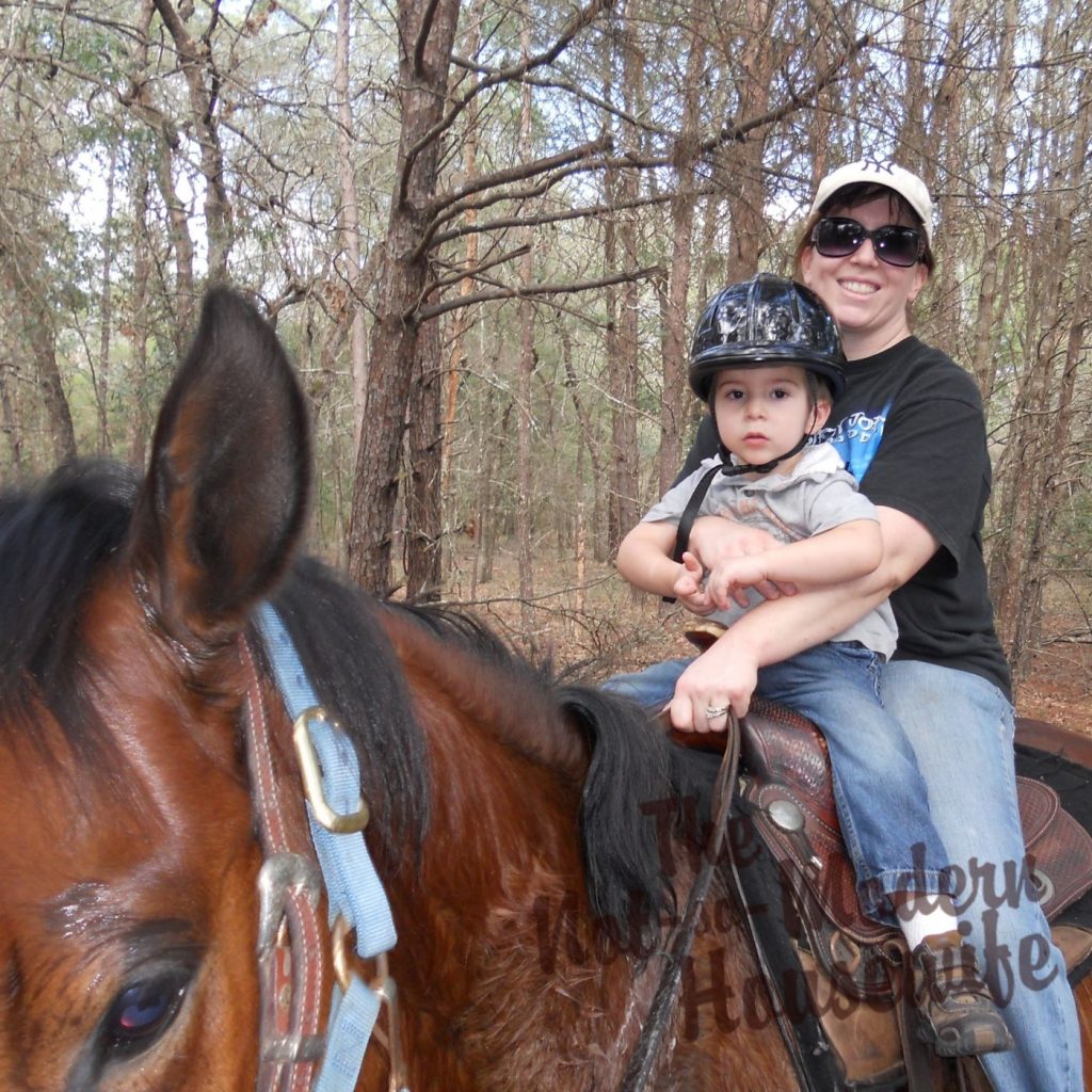 Bonnie Von Dohre and her son riding her horse Maverick in the woods, embracing a simple intentional living lifestyle.