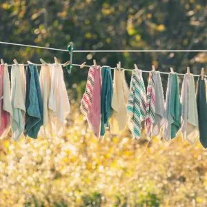 multicolored dishtowels hanging outside in the sun to dry on a clothesline with a line separator