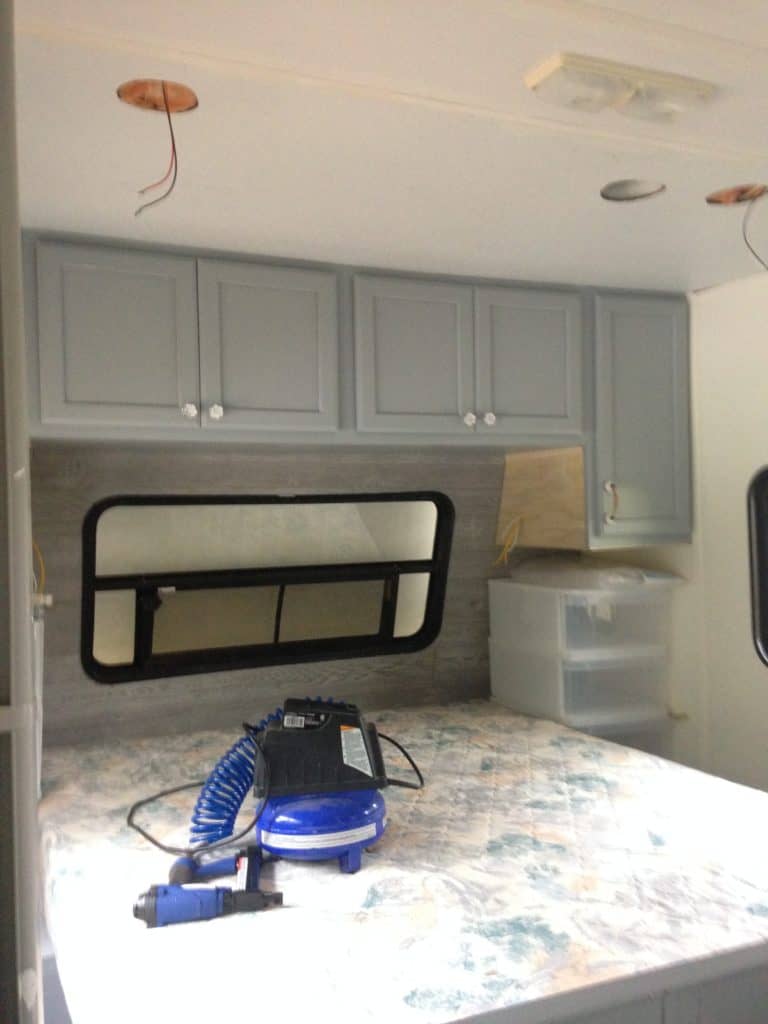 Picture of our RV bedroom after installation of the new cabinets and wood headboard wall
