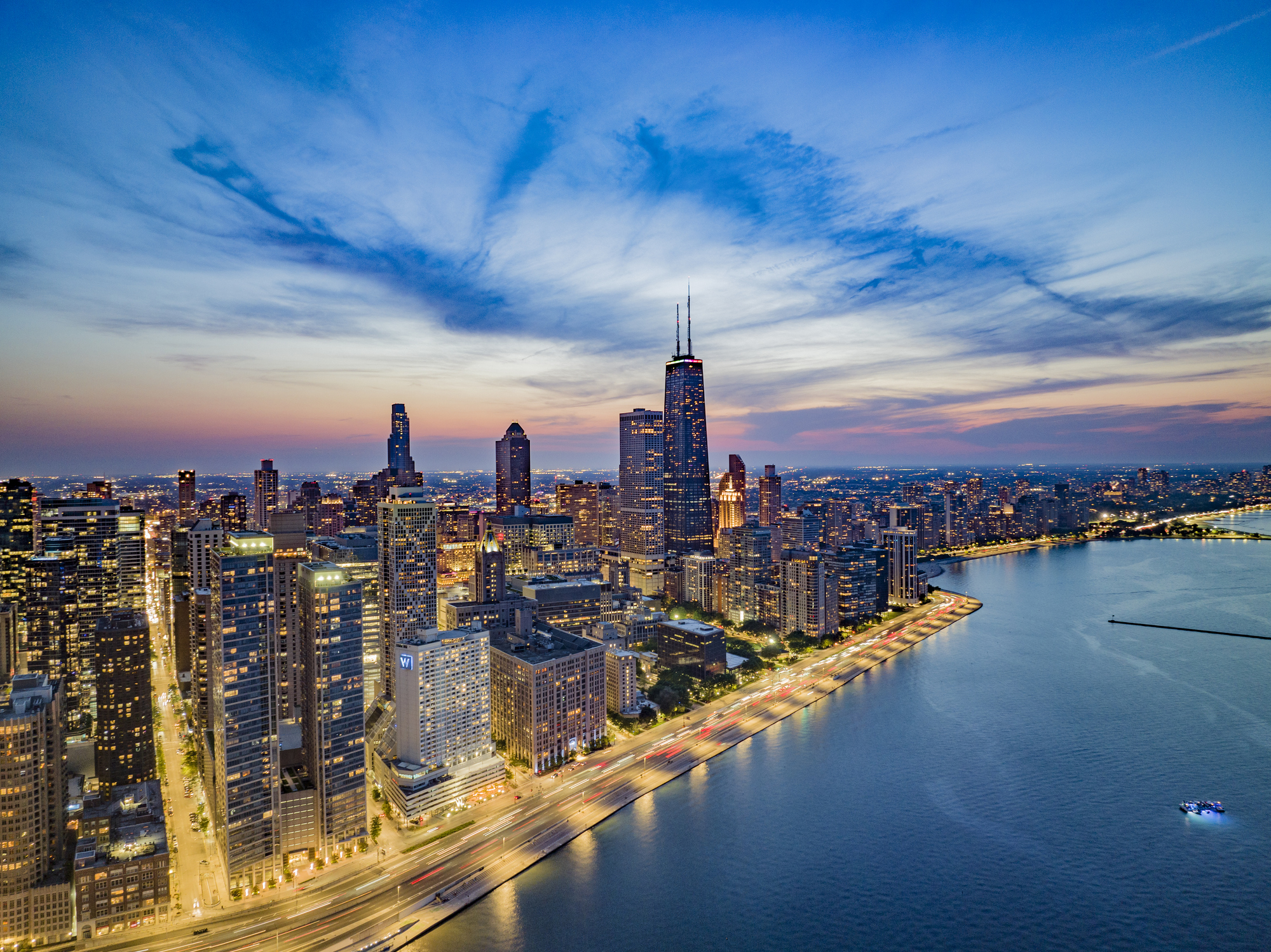 An evening view of the Chicago skyline, with the city’s towering skyscrapers illuminated by lights.