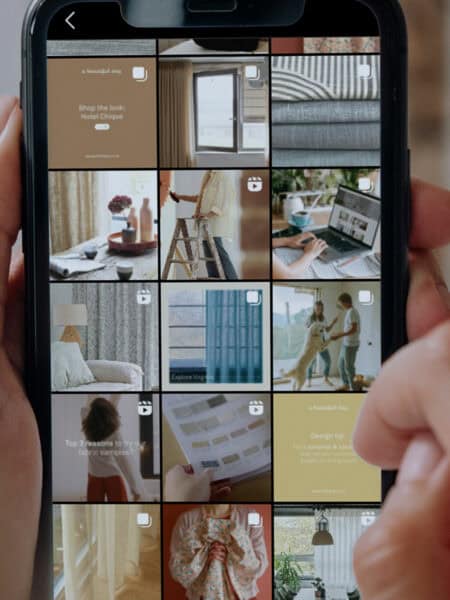 A person is holding a smartphone displaying an Instagram profile for A Beautiful Day brand with a grid of various home decor-related posts.