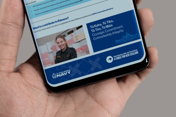 A person in a naval uniform smiling is displayed on a smartphone screen. The text below reads "Courage, Commitment, Comradeship, Integrity" next to logos for the New Zealand Navy.