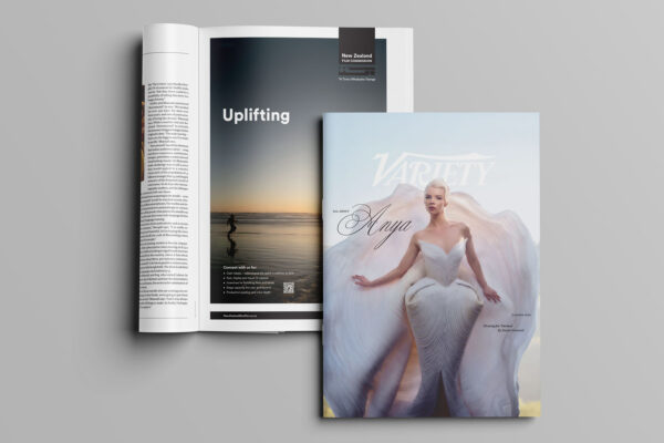 Open magazine shows an ad with "Uplifting" and a scenic view. On top, a closed Variety magazine features a person in an elegant, flowing white outfit with text "Anya." The background is a soft gradient.