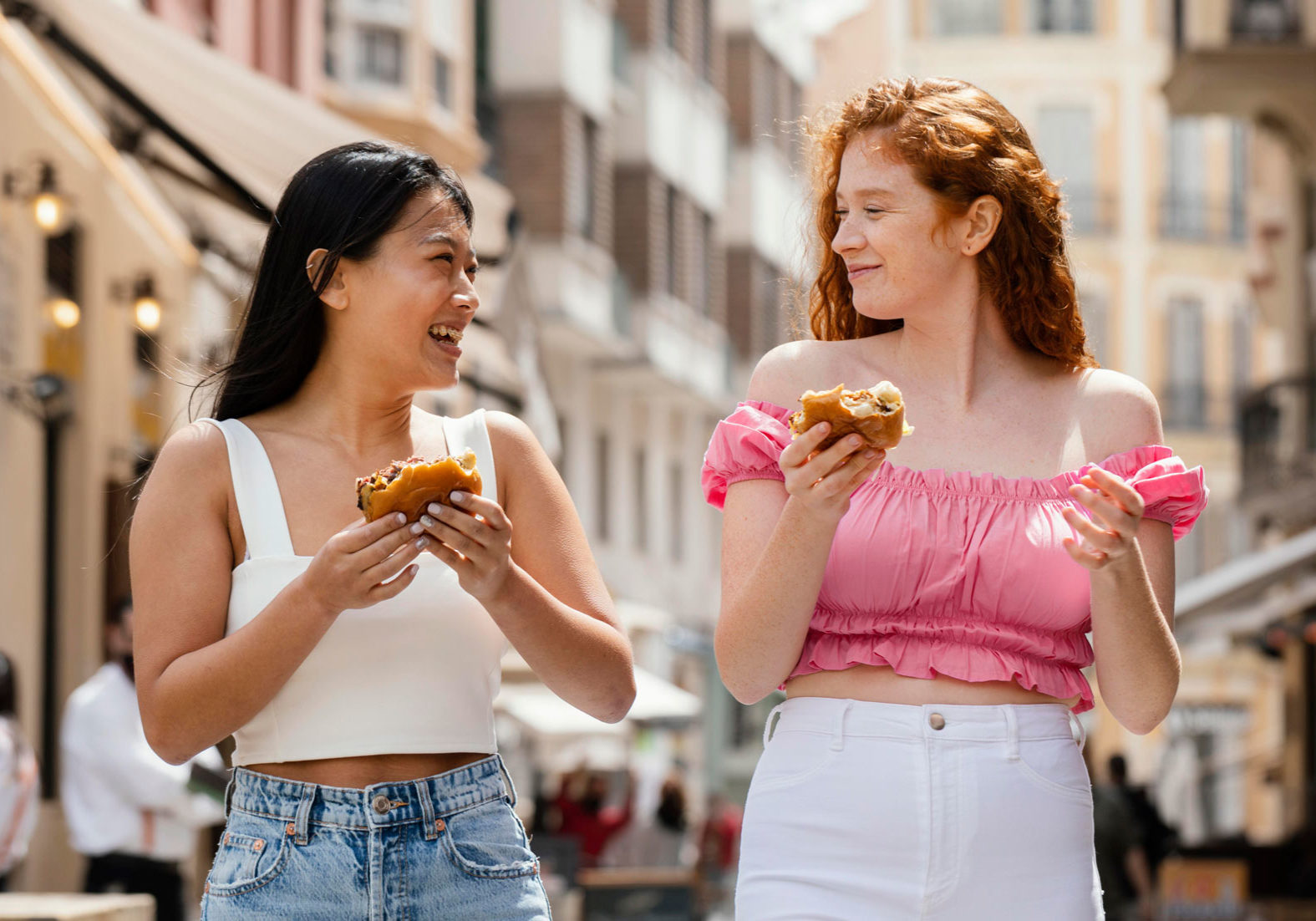 two girls walking and eating vegan burger sandwiches