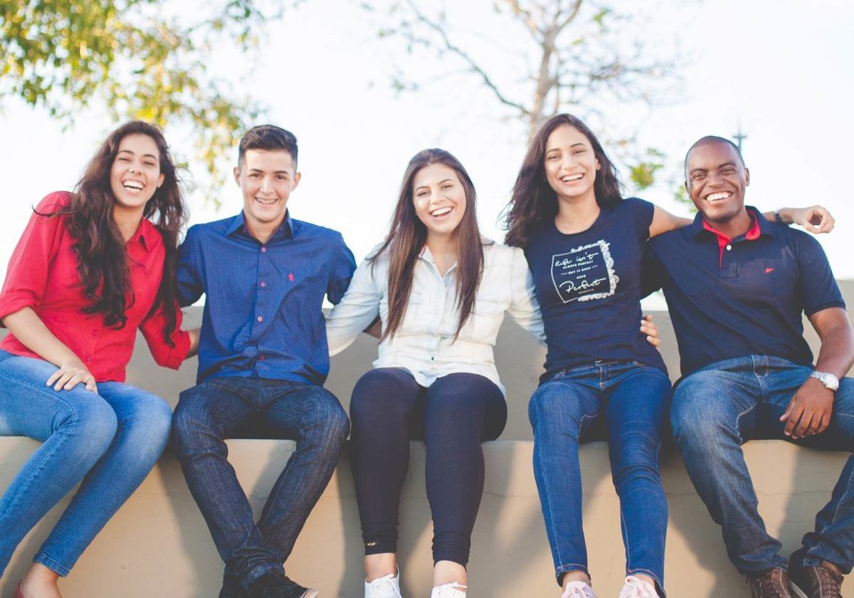 group of 5 young diversed people sitting and laughing