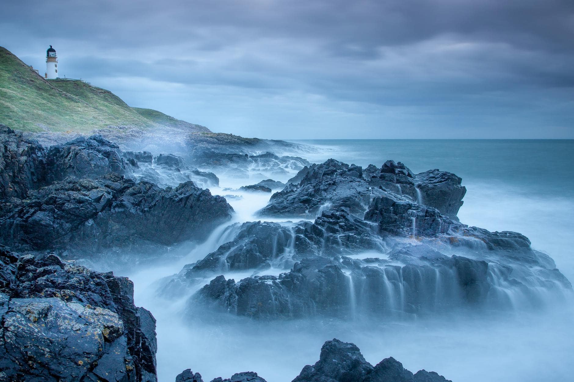 light house near rock formation body of water