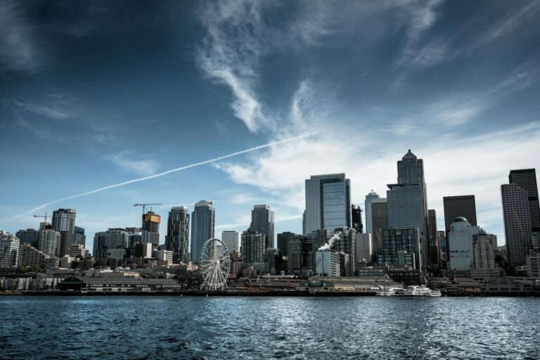 photo of white ferris wheel across city buildings