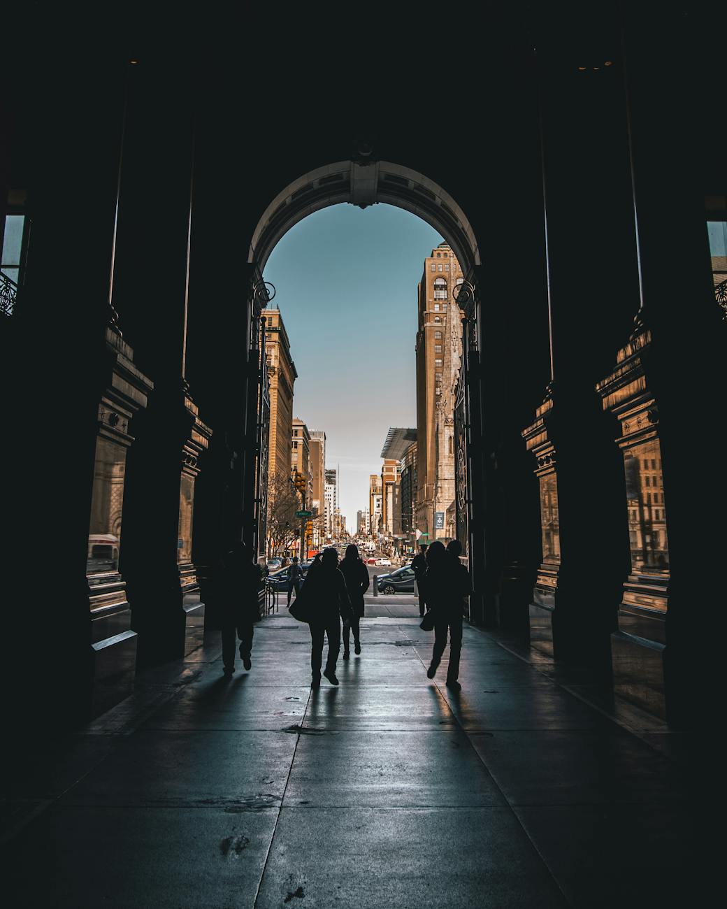 silhouette of people walking on a hallway leading to the streets