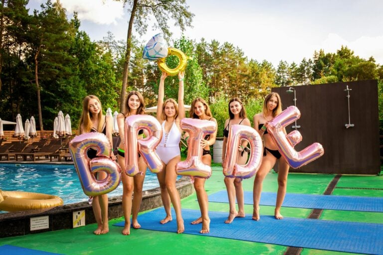 women holding balloons by the swimming pool