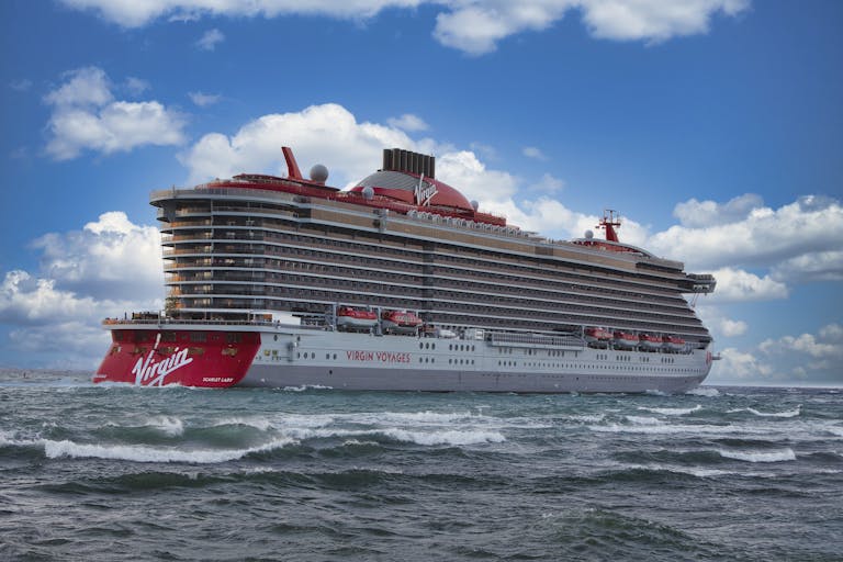 Experience the luxury of Virgin Voyages' Scarlet Lady cruise ship sailing through vibrant ocean waters.