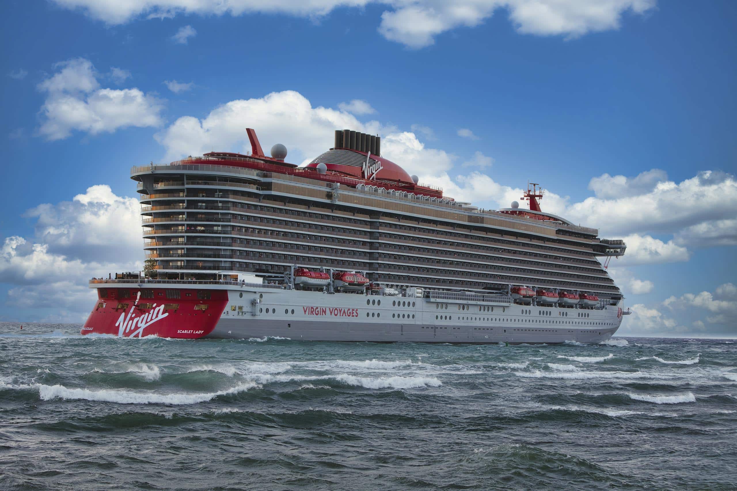 Experience the luxury of Virgin Voyages' Scarlet Lady cruise ship sailing through vibrant ocean waters.