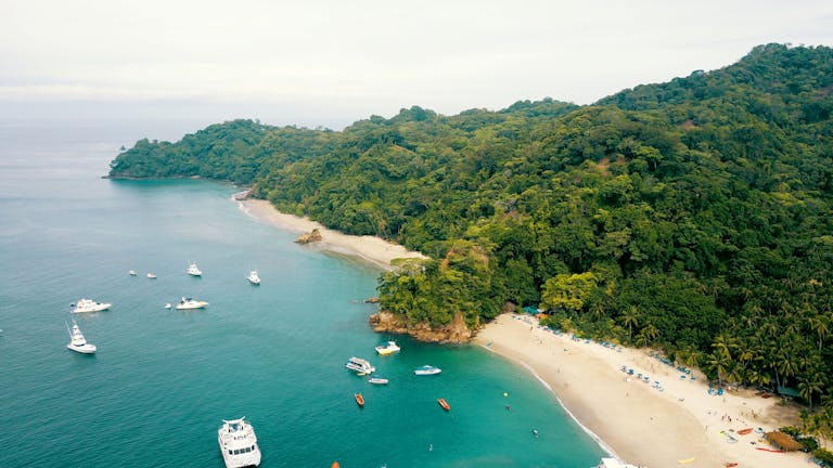 Stunning aerial view of a tropical beach in Costa Rica with boats and lush greenery.