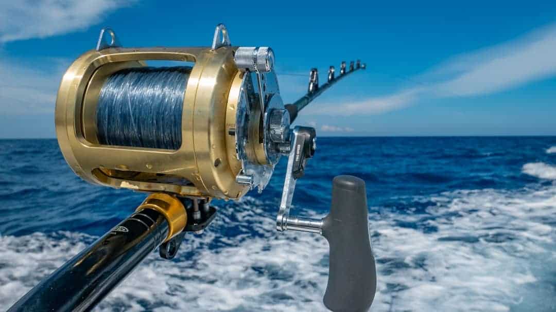A rod and reel set up in a boat rod holder over the Caribbean Sea.