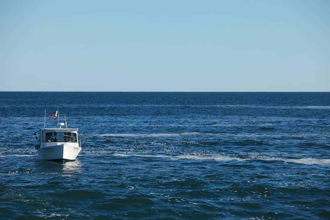 A white sportfishing boat running across open ocean water.