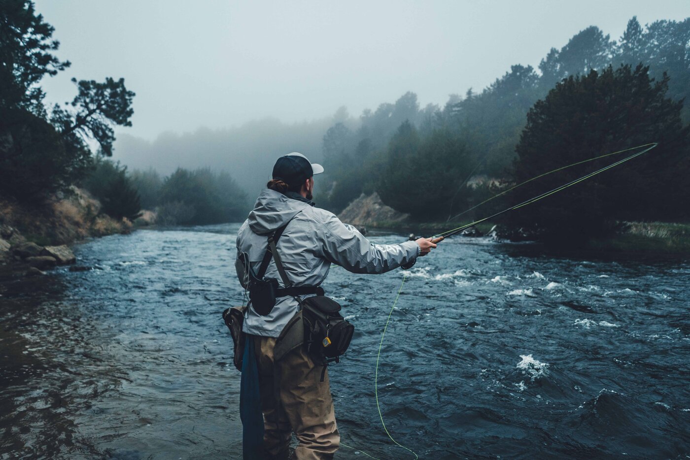 Angler casting into a misty river