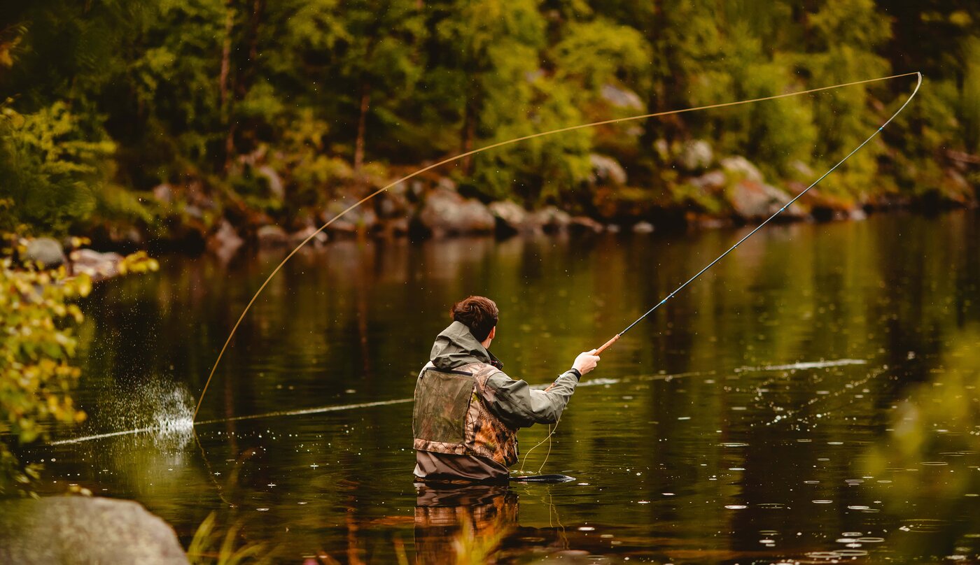 Fly angler working a river in warm evening backlight