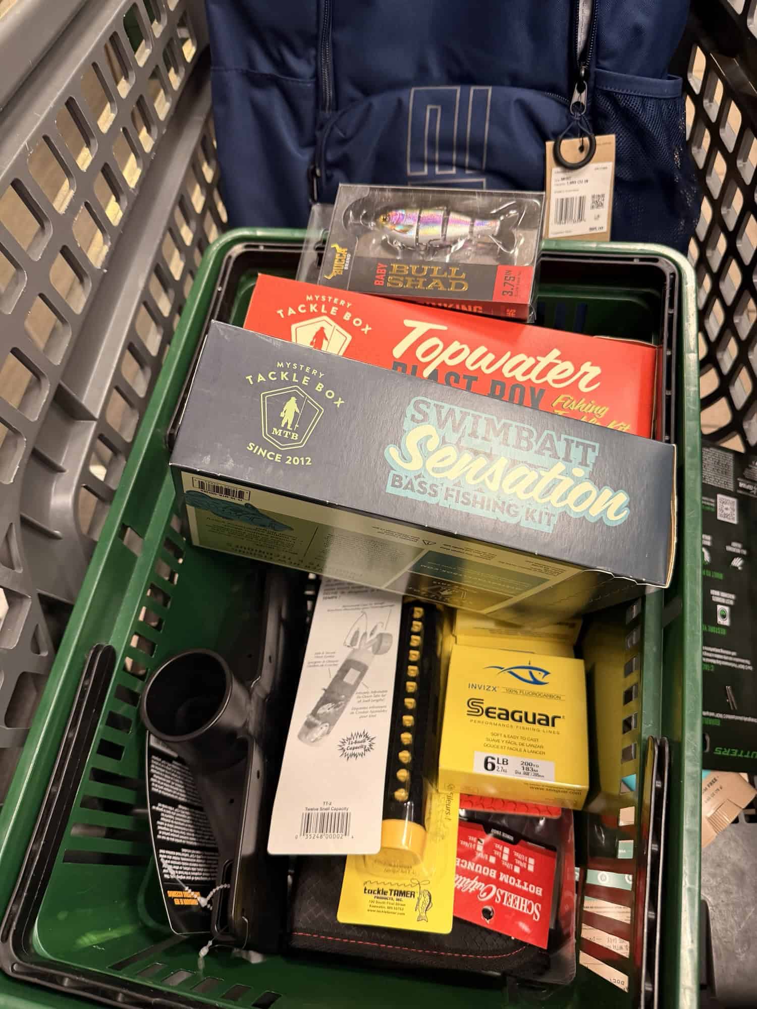 Green shopping basket of bass kits, a Bull Shad lure, Seaguar line, and other tackle