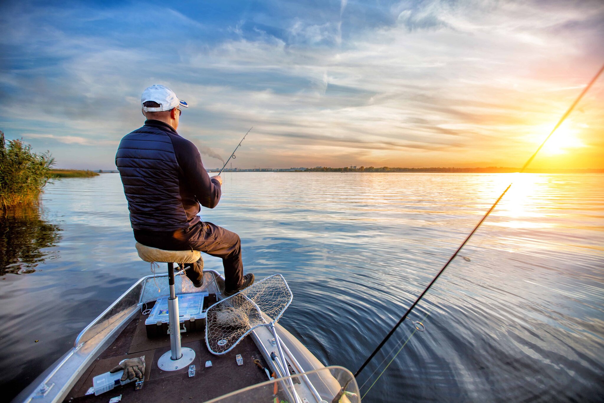 Angler fishing from a small boat on an autumn lake