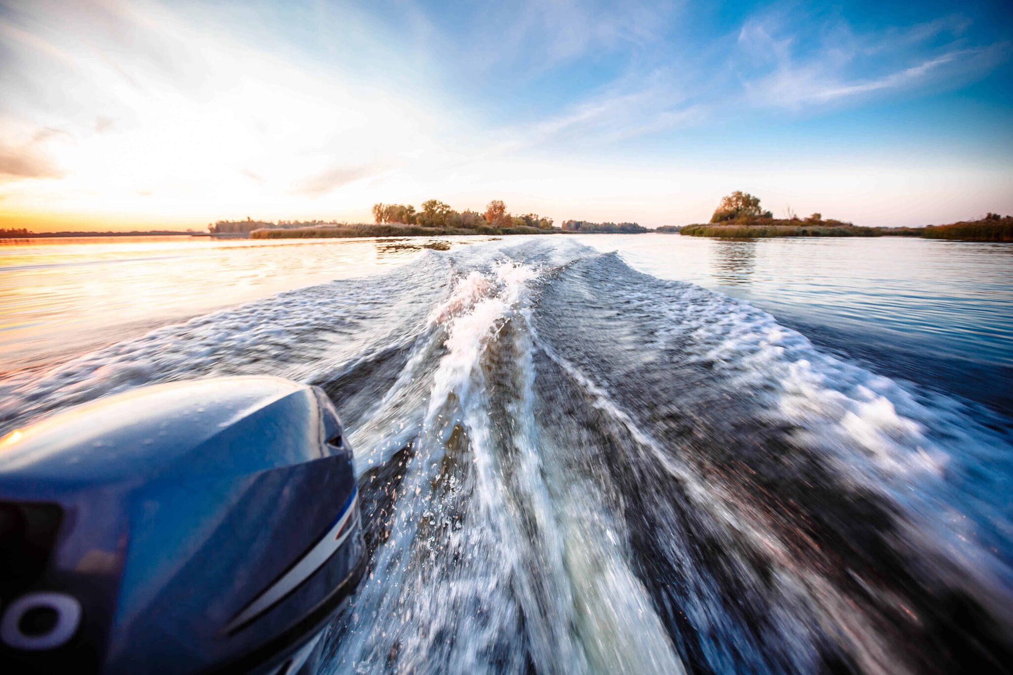 Boat wake stretching across a deep river from coast to coast
