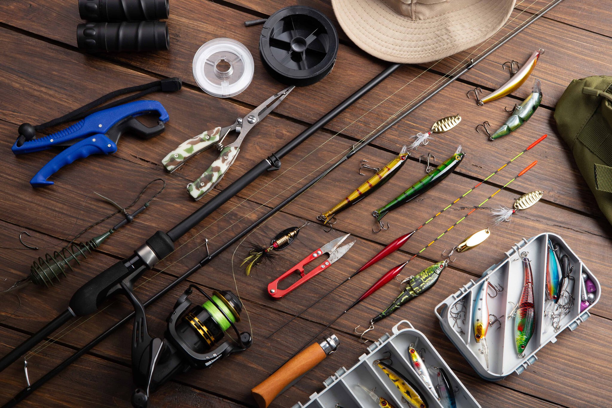 Spinning rod, hooks, and lures arranged on a wooden background
