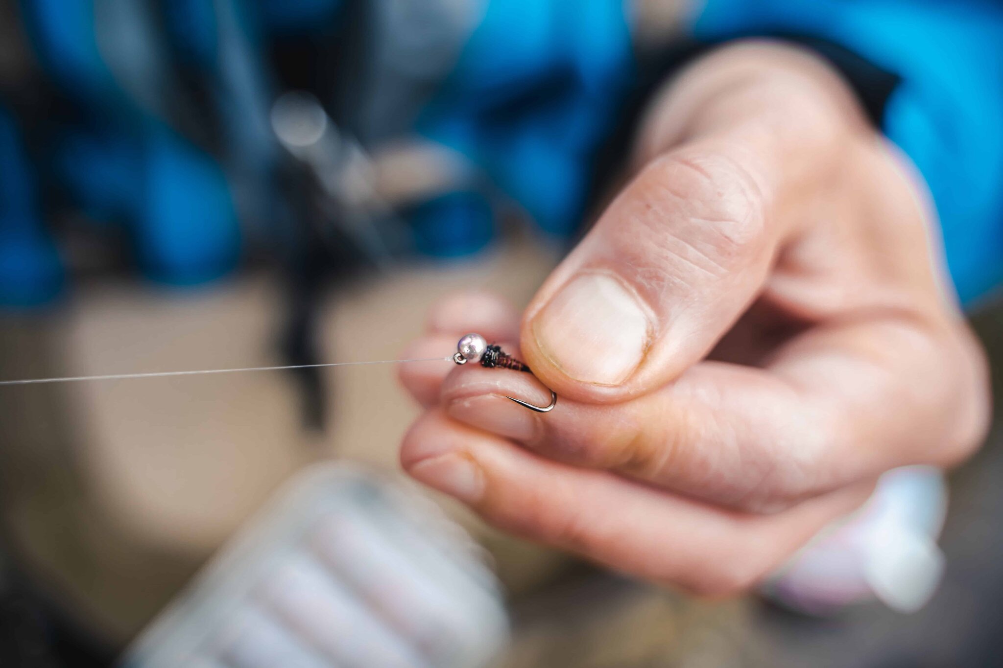 Close-up of an angler tying a fine fly-fishing knot by hand