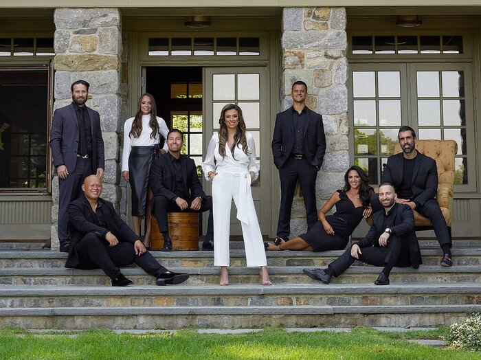 Corporate team dressed in black and white posed on the stone steps of a residential property.