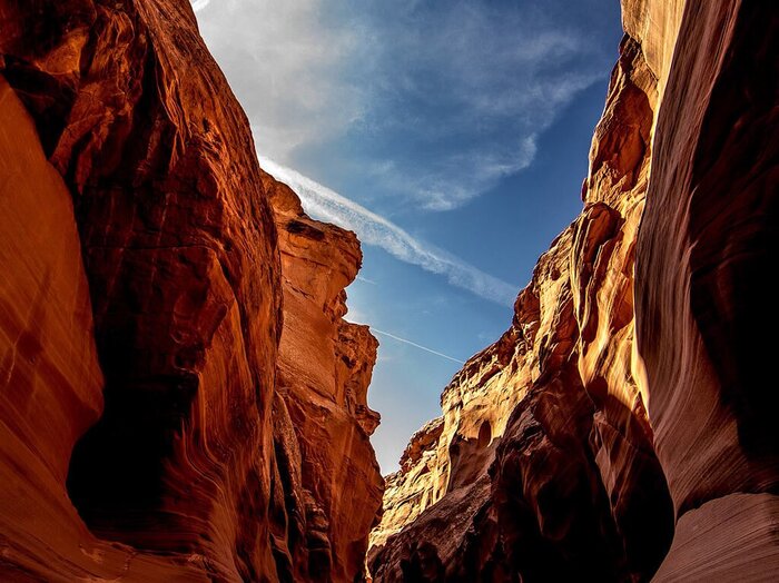 Red sandstone walls of Antelope Canyon opening toward a blue desert sky.