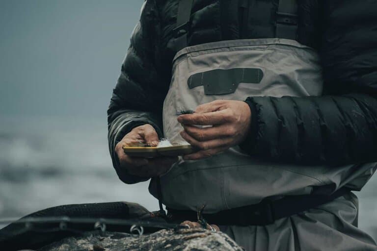 Person outdoors checking a phone before fishing, representing a regulation check before finishing the rig