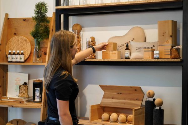 Kundin betrachtet Zirbenprodukte im AlpenXund-Shop – natürliche Produkte aus Zirbenholz für Wohlbefinden und Raumklima.