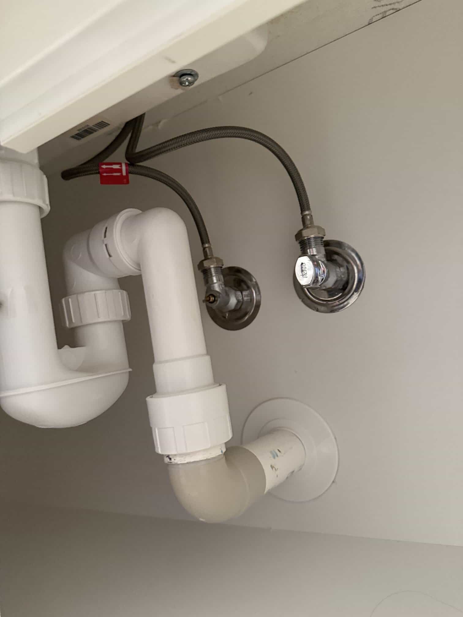 Corroded flexi hoses connected to old basin mixer in Kingston apartment.