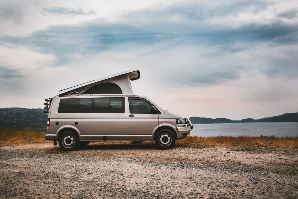 Camper con tetto sollevabile parcheggiato vicino a un lago al tramonto