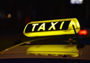 Insegna gialla luminosa con scritta taxi su tetto auto, ideale per identificare servizio taxi notturno