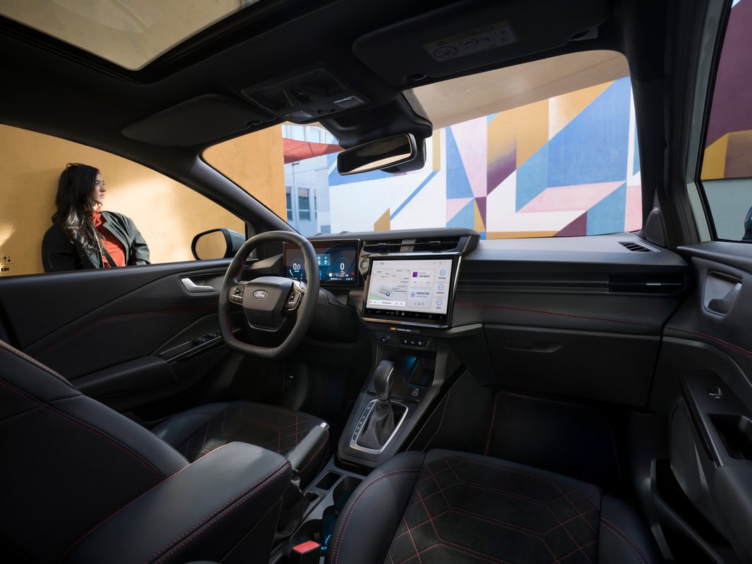 Interni Ford Puma 2024 con plancia digitale, sedili in pelle nera con cuciture rosse e display centrale touchscreen.