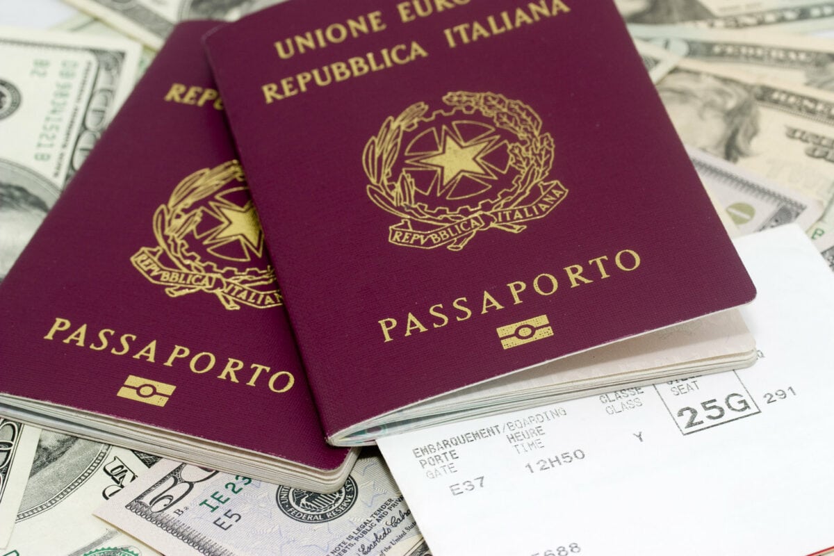 Due passaporti italiani su banconote e biglietto aereo.