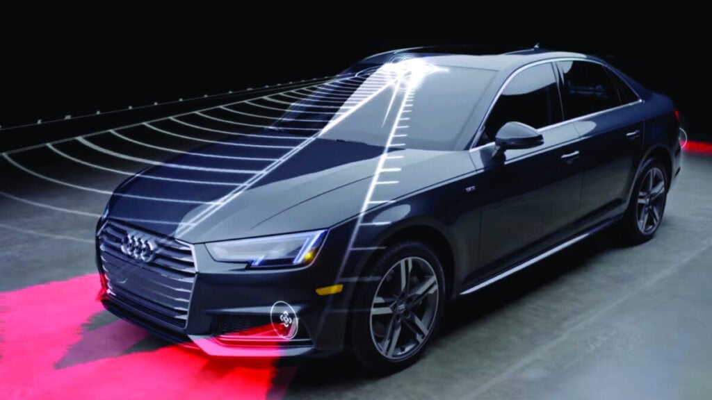 Audi nera con sistema ADAS visualizzato tramite grafica digitale che evidenzia sensori radar e lidar per assistenza alla guida autonoma su sfondo scuro.