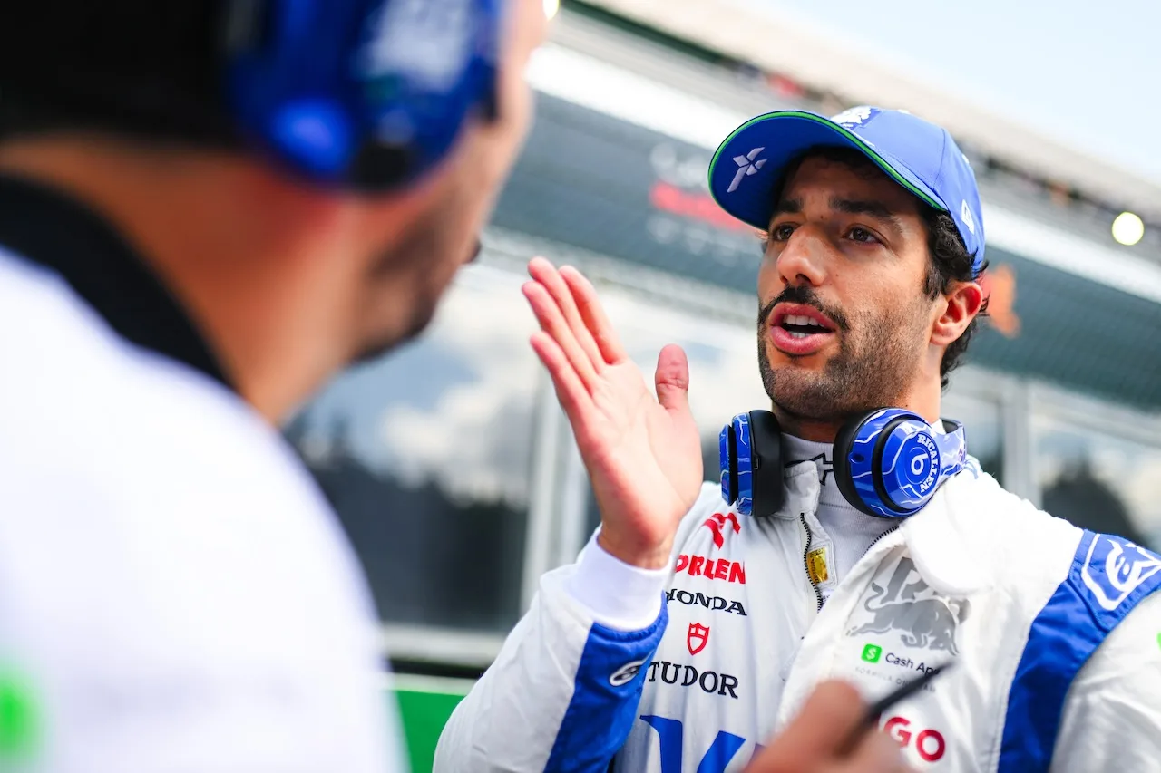 Daniel Ricciardo con tuta e cappellino del team di Formula 1, parla con un membro dello staff ai box.