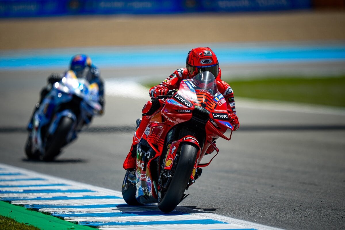 MotoGP in pista, Marc Marquez sulla Ducati durante una gara, dinamismo e velocità, con altri motociclisti sullo sfondo, circuito di gara, immagini di motorsport e passione per le corse.